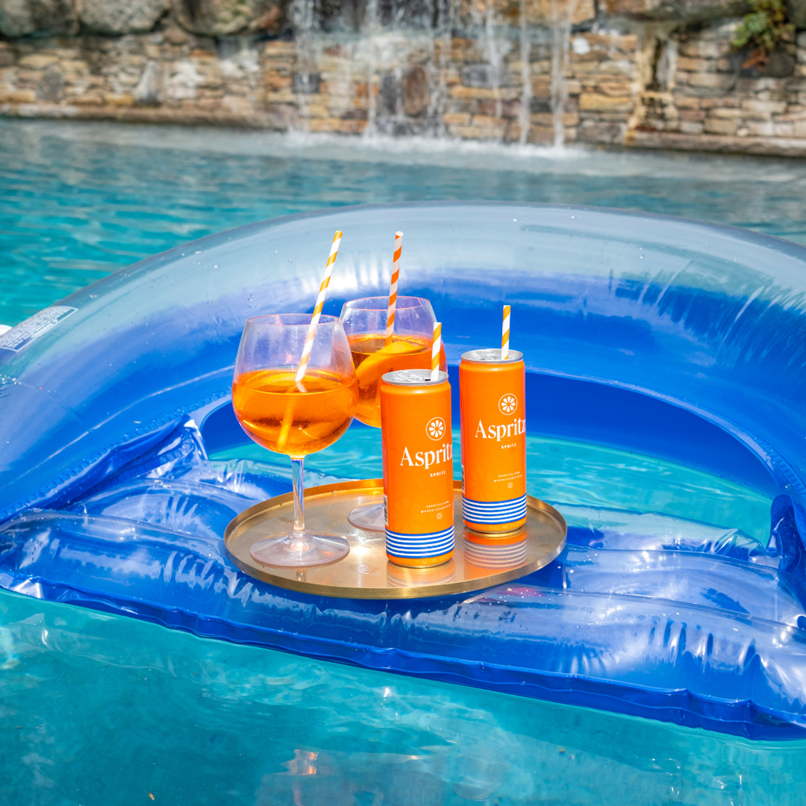 Inflatable pool float with drinks and Aspritza cans in a pool setting.